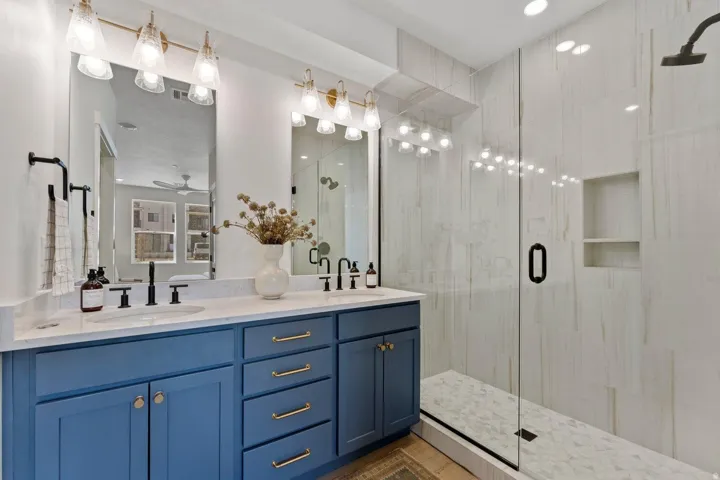 Full bathroom featuring a shower stall, double vanity, and ceiling fan