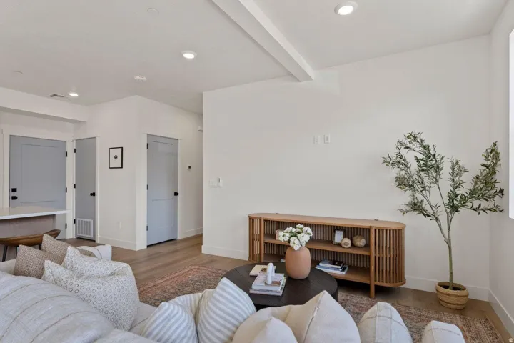 Living room with wood finished floors, beam ceiling, and recessed lighting
