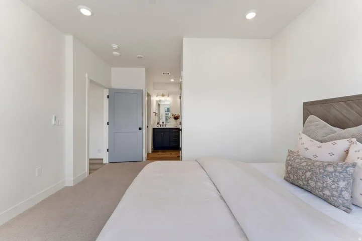 Carpeted bedroom with connected bathroom and recessed lighting