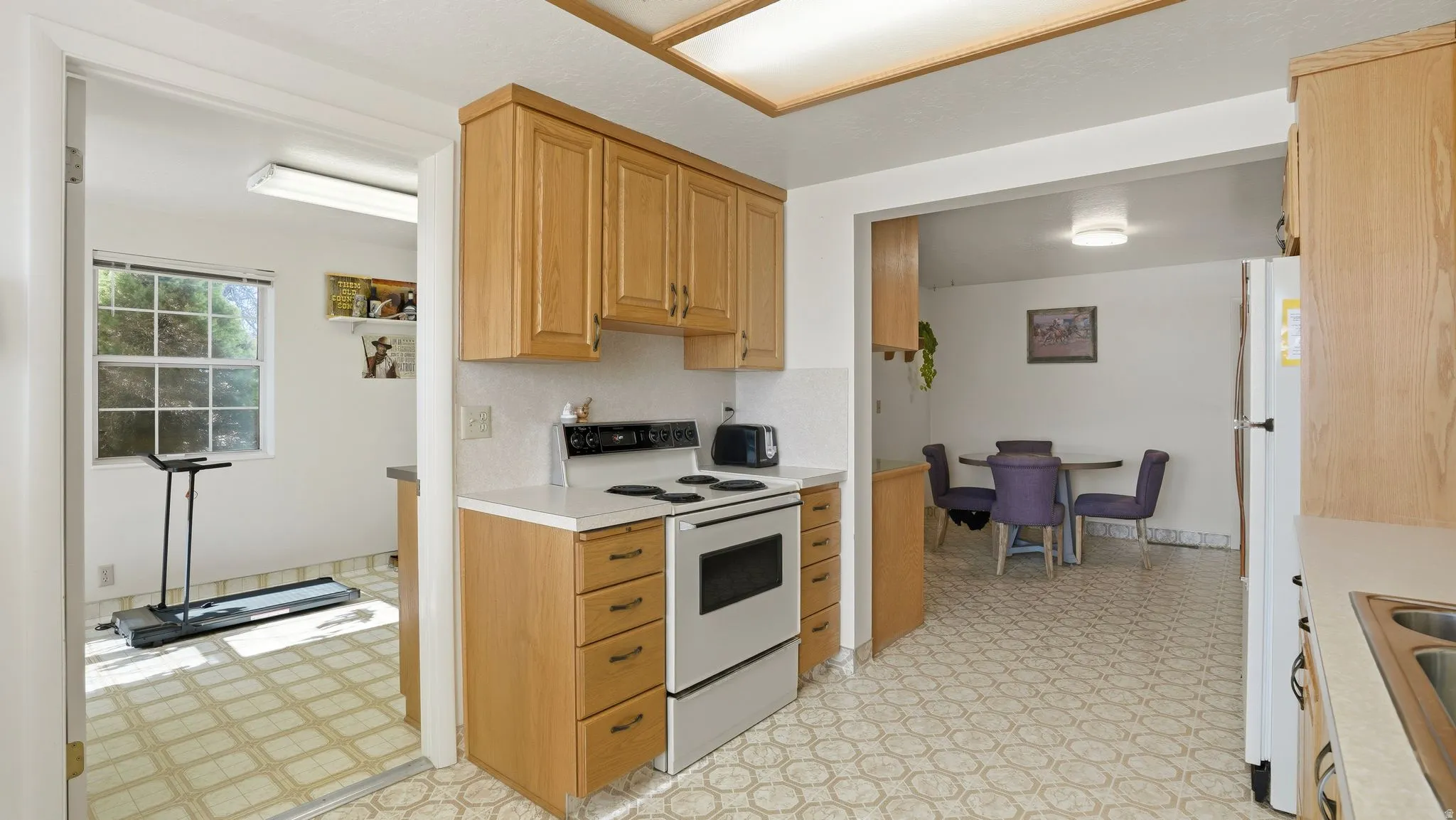 Kitchen with light flooring, white appliances, light countertops, and light wood finish cabinets