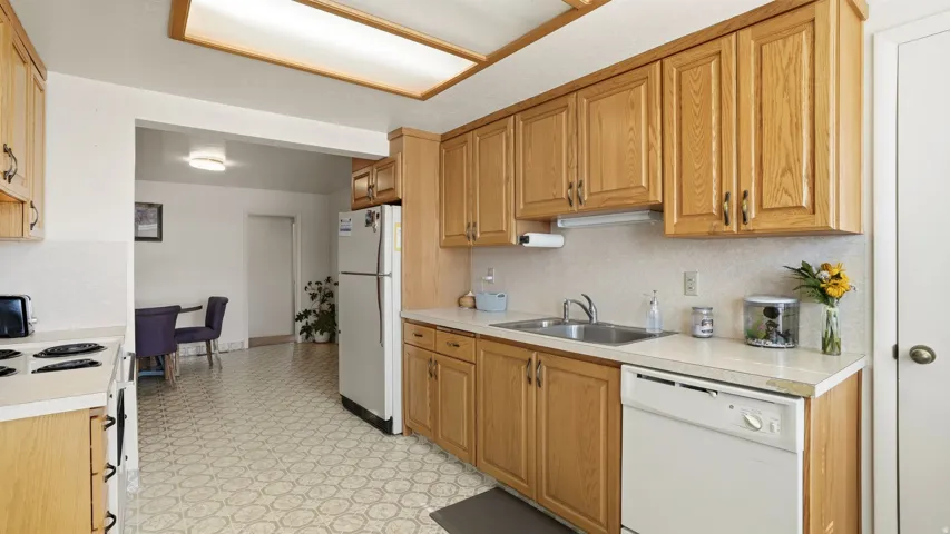 Kitchen with white appliances, light countertops, light floors, and wood finish cabinetry