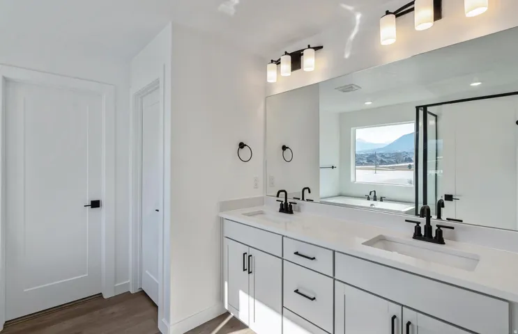 Owner's Bathroom with double vanity, light wood-type flooring, a shower stall, and a garden tub