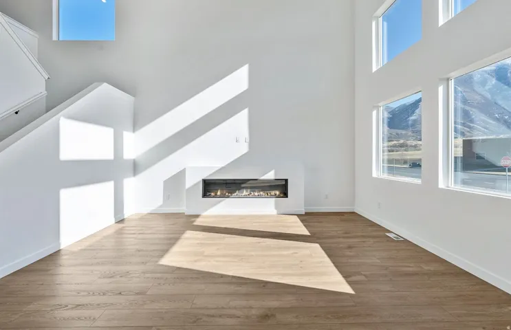 Unfurnished living room with a glass covered fireplace, a high ceiling, and wood finished floors