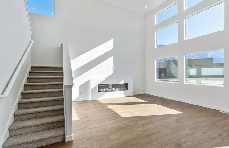 Unfurnished living room featuring a high ceiling, a glass covered fireplace, light wood-type flooring, and healthy amount of natural light