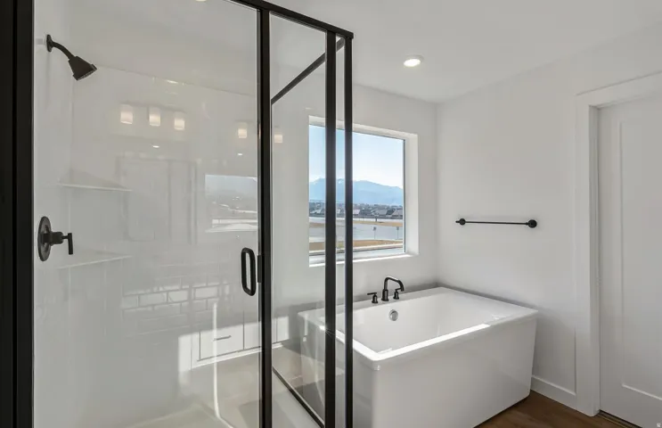 Owner's Full bathroom featuring a soaking tub, a shower stall, a mountain view, dark wood-type flooring, and recessed lighting