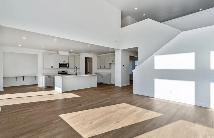 Unfurnished living room with light wood-style flooring, recessed lighting, and a high ceiling