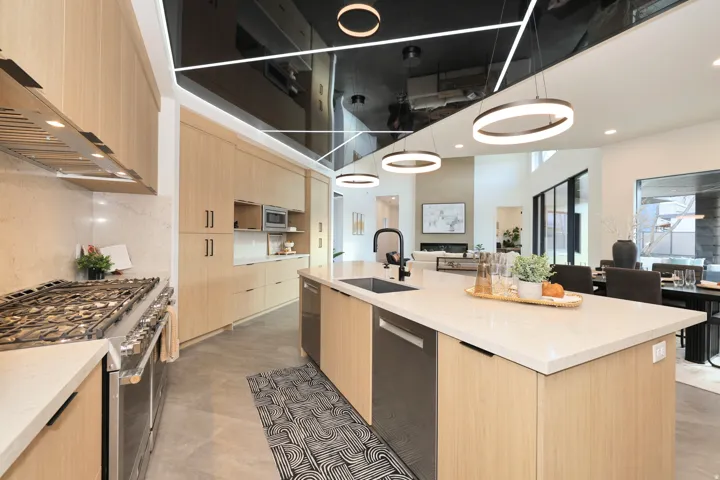 Kitchen featuring light wood finish cabinets, stainless steel appliances, light stone counters, modern cabinets, and pendant lighting