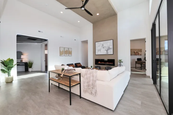 Living room featuring a high ceiling, a ceiling fan, a fireplace, and concrete floors