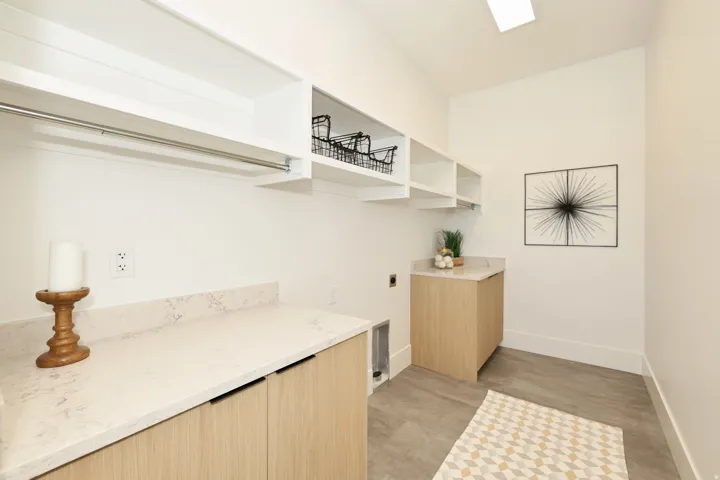Laundry room with electric dryer hookup, concrete flooring, and cabinet space