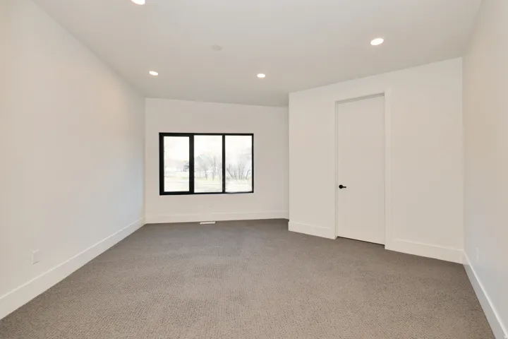Empty room with light carpet and recessed lighting