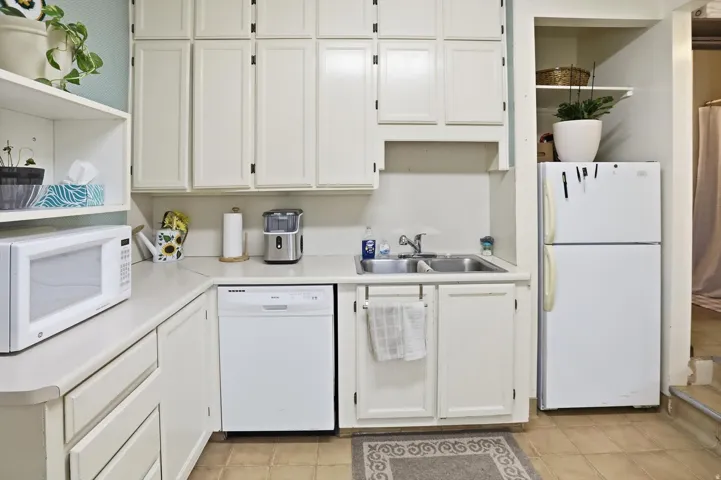 Kitchen featuring open shelves, white appliances, white cabinetry, light countertops, and light tile patterned floors