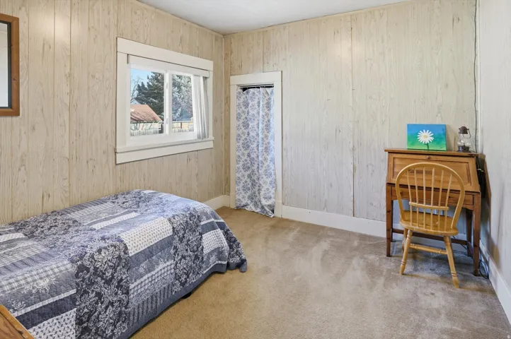 Bedroom with light colored carpet and wooden walls