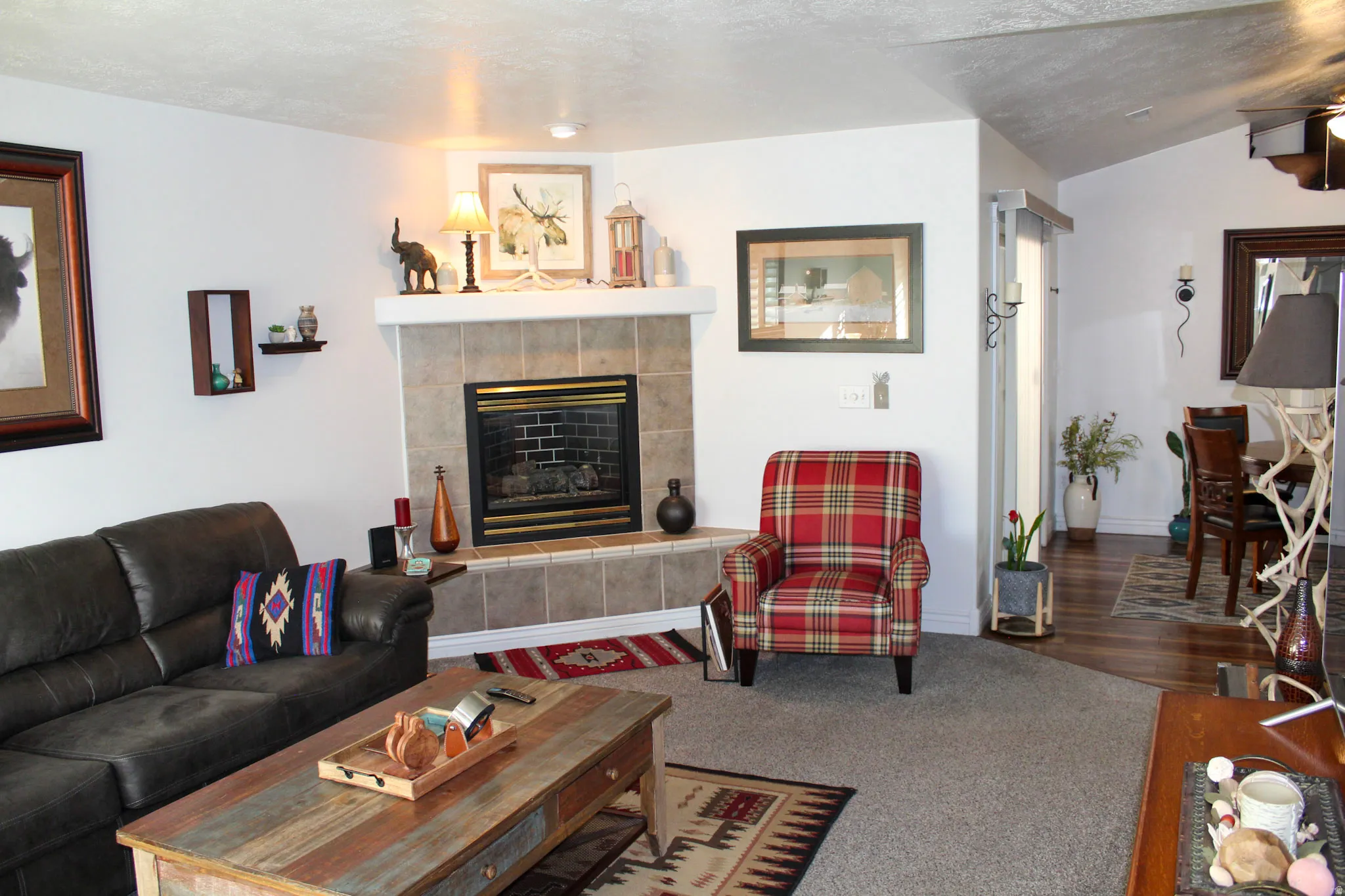 Living room with a fireplace, dark carpet, and vaulted ceiling