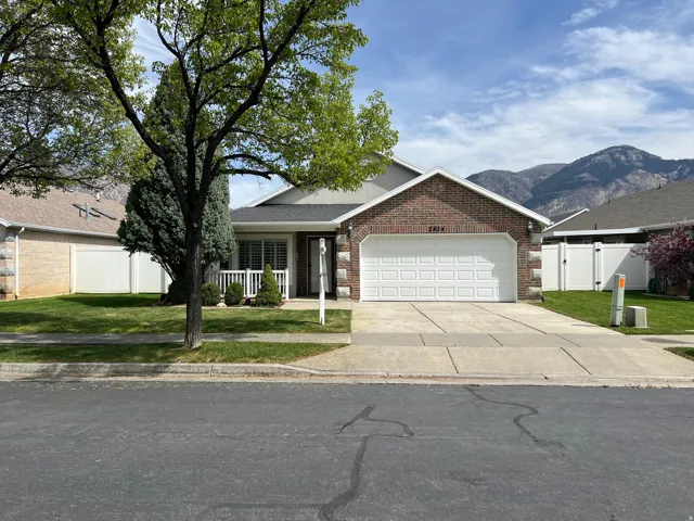 Ranch-style home with an attached garage, brick siding, a gate, concrete driveway, and a mountain view