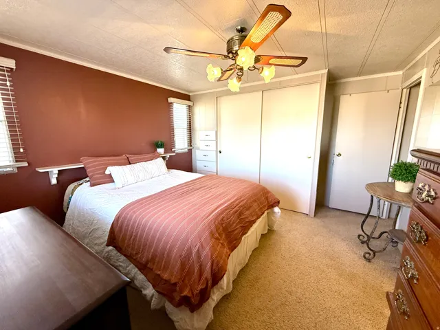 Bedroom featuring a closet, carpet flooring, a textured ceiling, ceiling fan, and crown molding