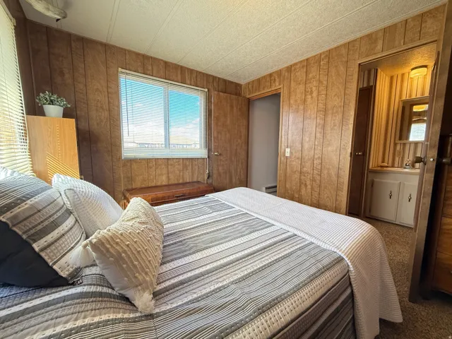 Carpeted bedroom featuring wooden walls and a baseboard heating unit