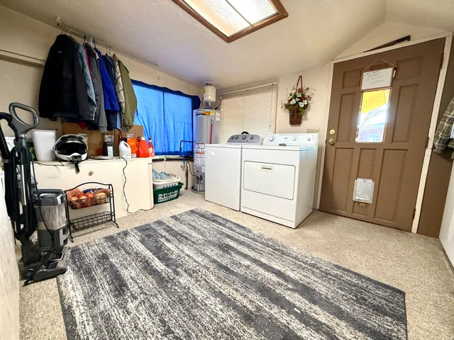 Laundry room with gas water heater, independent washer and dryer, and a textured ceiling