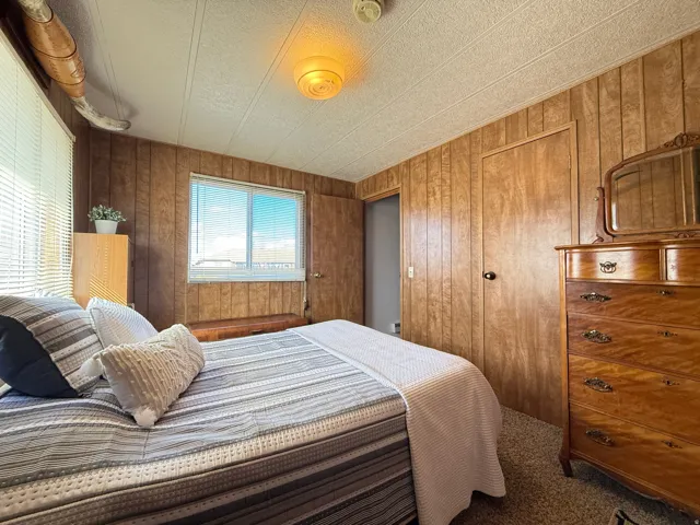 Carpeted bedroom with a closet, a textured ceiling, and wooden walls