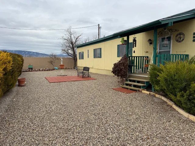 Front view of property featuring a xeriscaped yard, mountain view, a patio, and covered porch