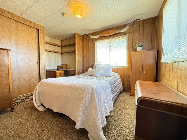 Carpeted bedroom featuring wooden walls, a closet, and a textured ceiling