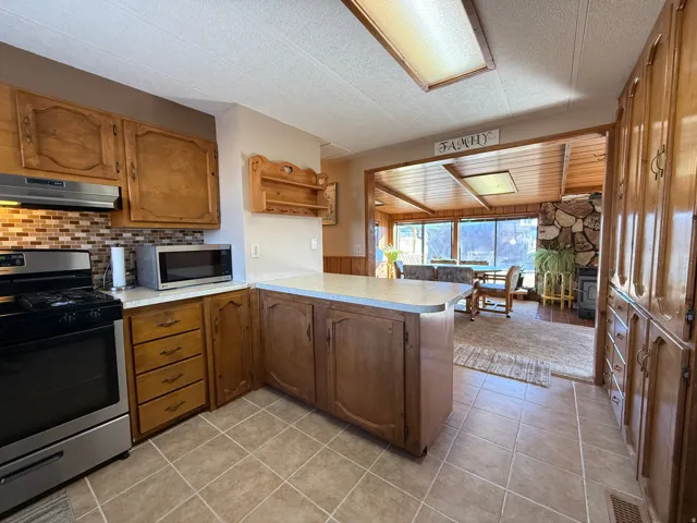 Kitchen featuring stainless steel appliances, a textured ceiling, light countertops, wood finish cabinetry, and a peninsula