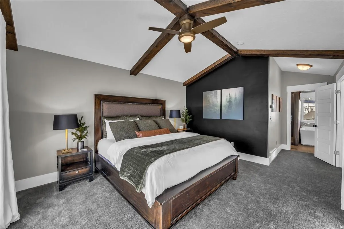 Carpeted bedroom with beamed ceiling and a ceiling fan