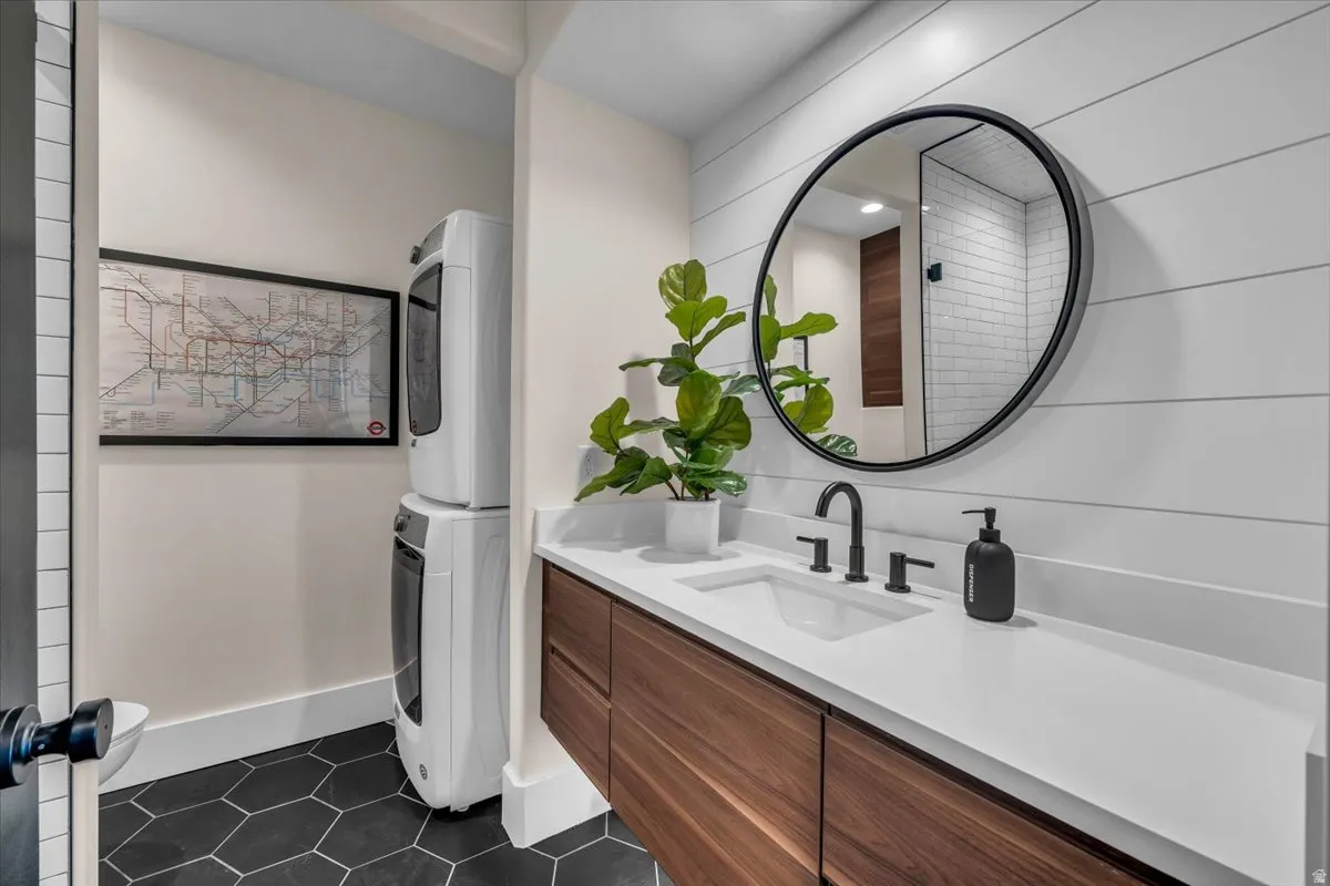 Bathroom featuring vanity, dark tile patterned flooring, and stacked washer / dryer