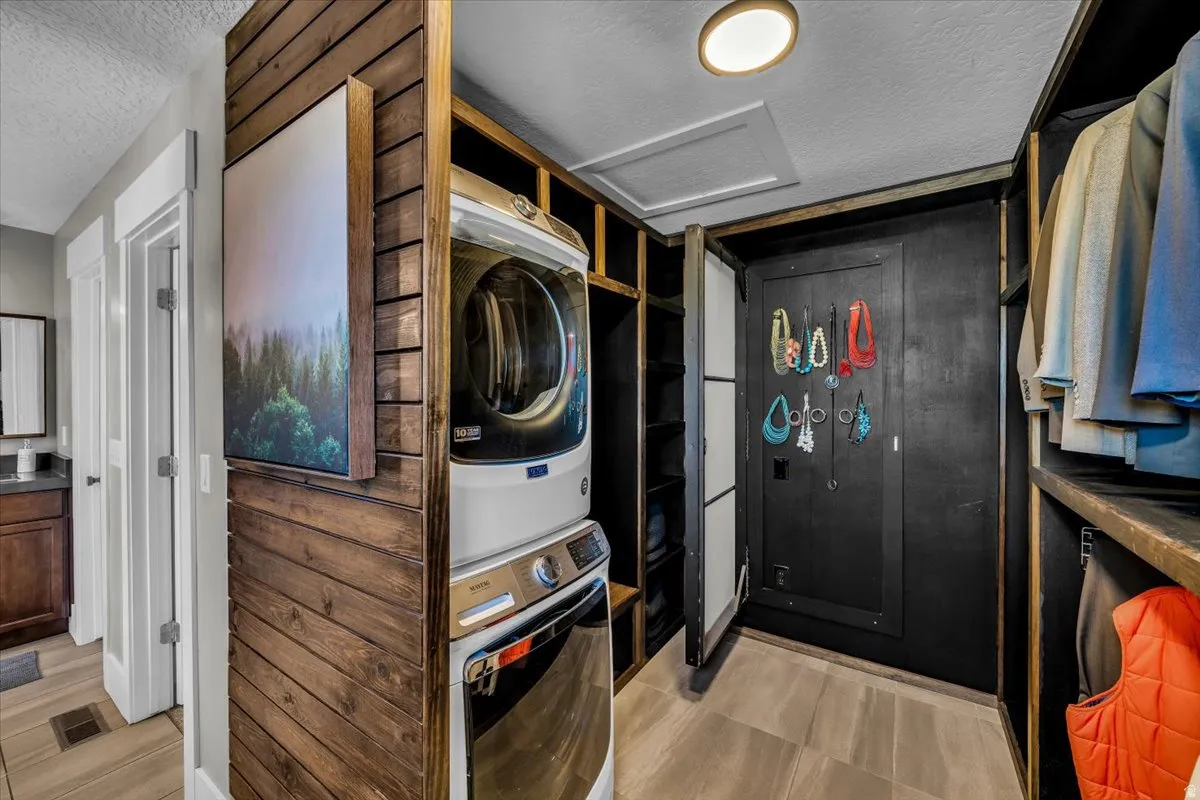 Laundry area with a textured ceiling and stacked washing machine and dryer