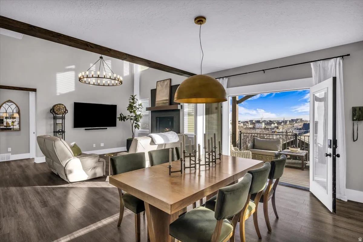 Dining area with dark wood-style floors, a textured ceiling, a chandelier, and beamed ceiling