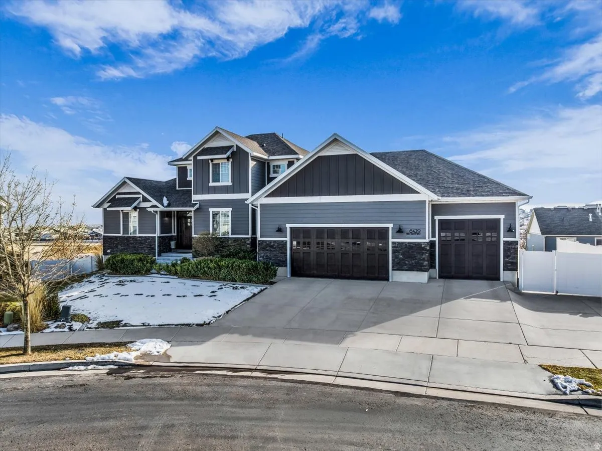 Craftsman-style home with stone siding, a garage, concrete driveway, and board and batten siding