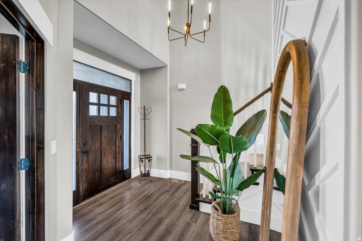 Foyer entrance with dark wood-style flooring and a chandelier