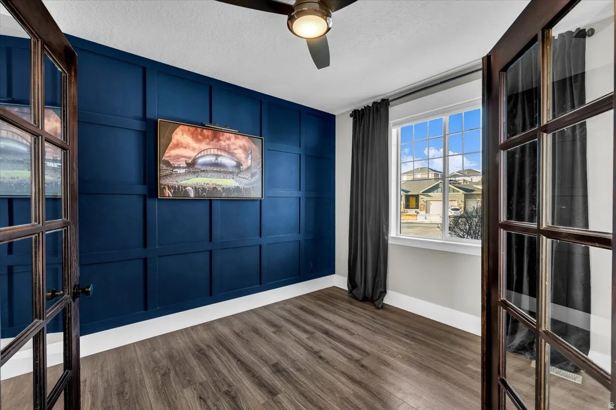Spare room featuring a decorative wall, dark wood-style flooring, a textured ceiling, and a ceiling fan