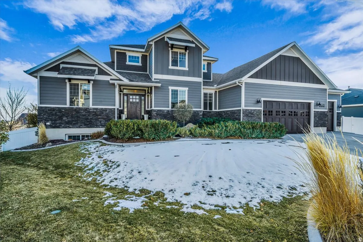 Craftsman inspired home with stone siding, board and batten siding, an attached garage, and roof with shingles