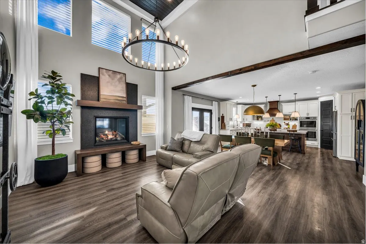 Living room featuring dark wood finished floors, a glass covered fireplace, a high ceiling, and a chandelier