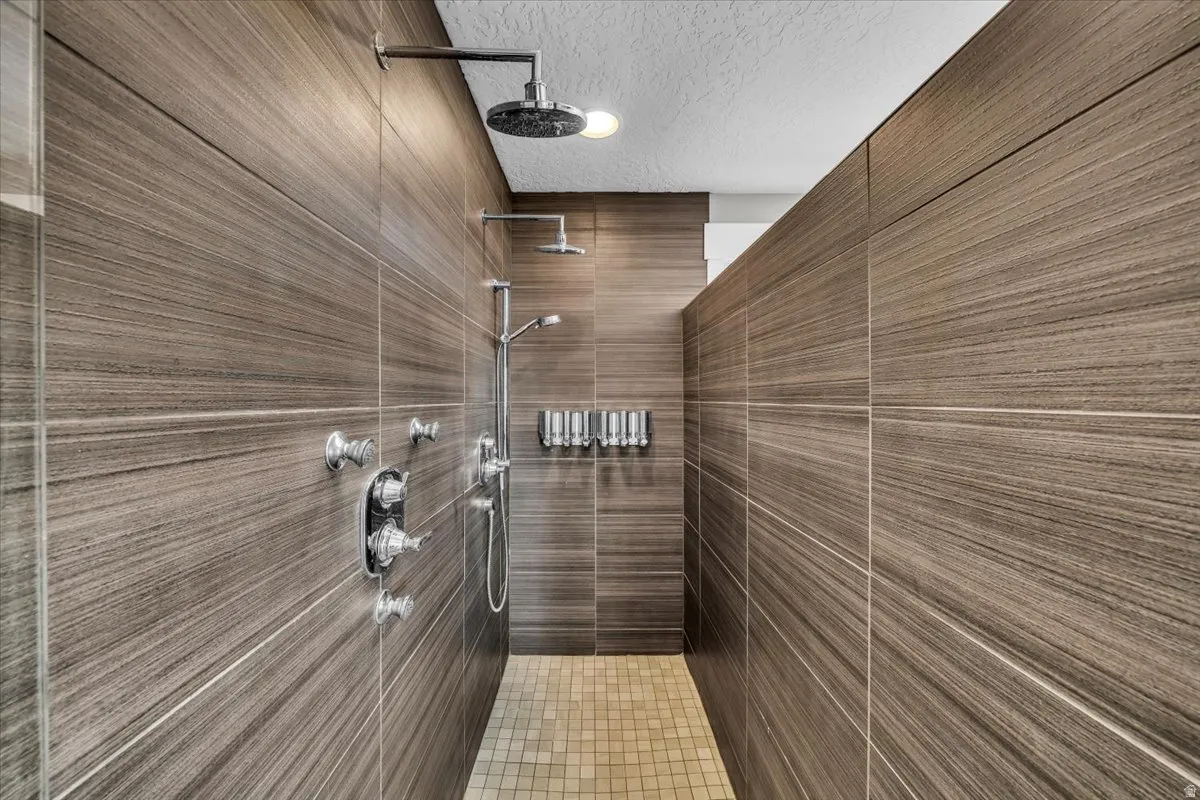 Full bath featuring a textured ceiling and a tile shower
