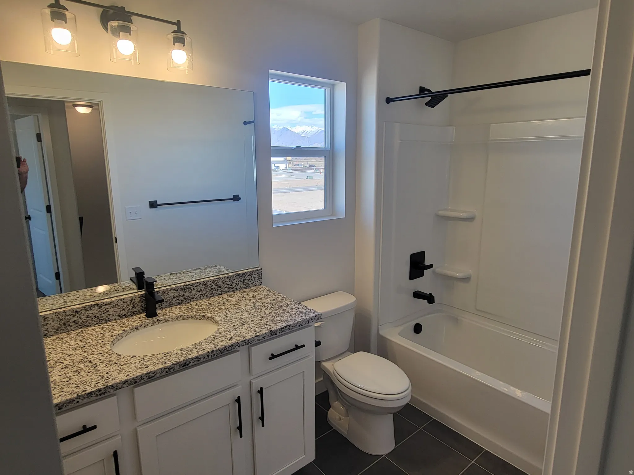 Bathroom featuring shower / bathtub combination, vanity, and dark tile patterned floors