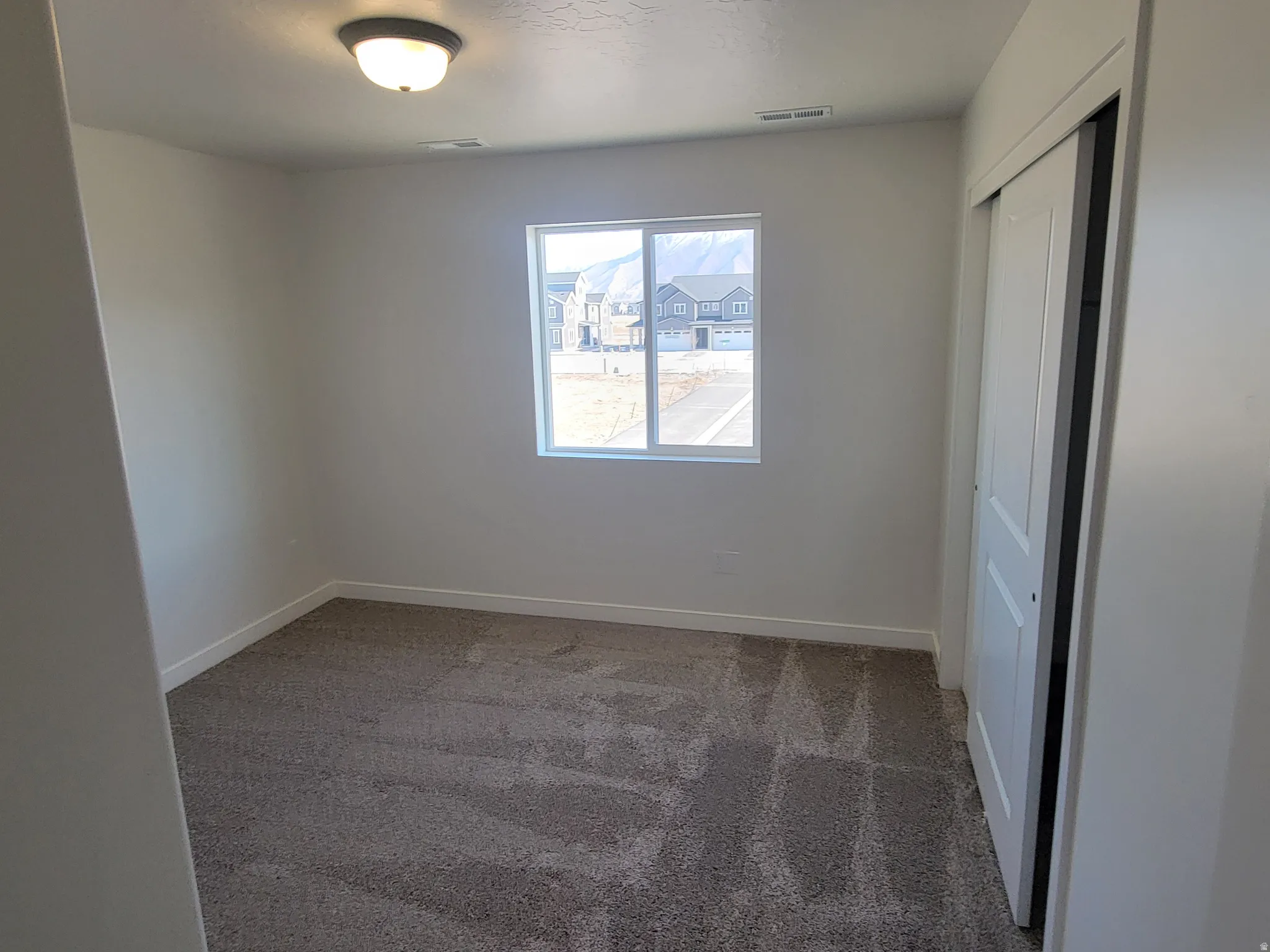 Unfurnished bedroom with light carpet and a closet