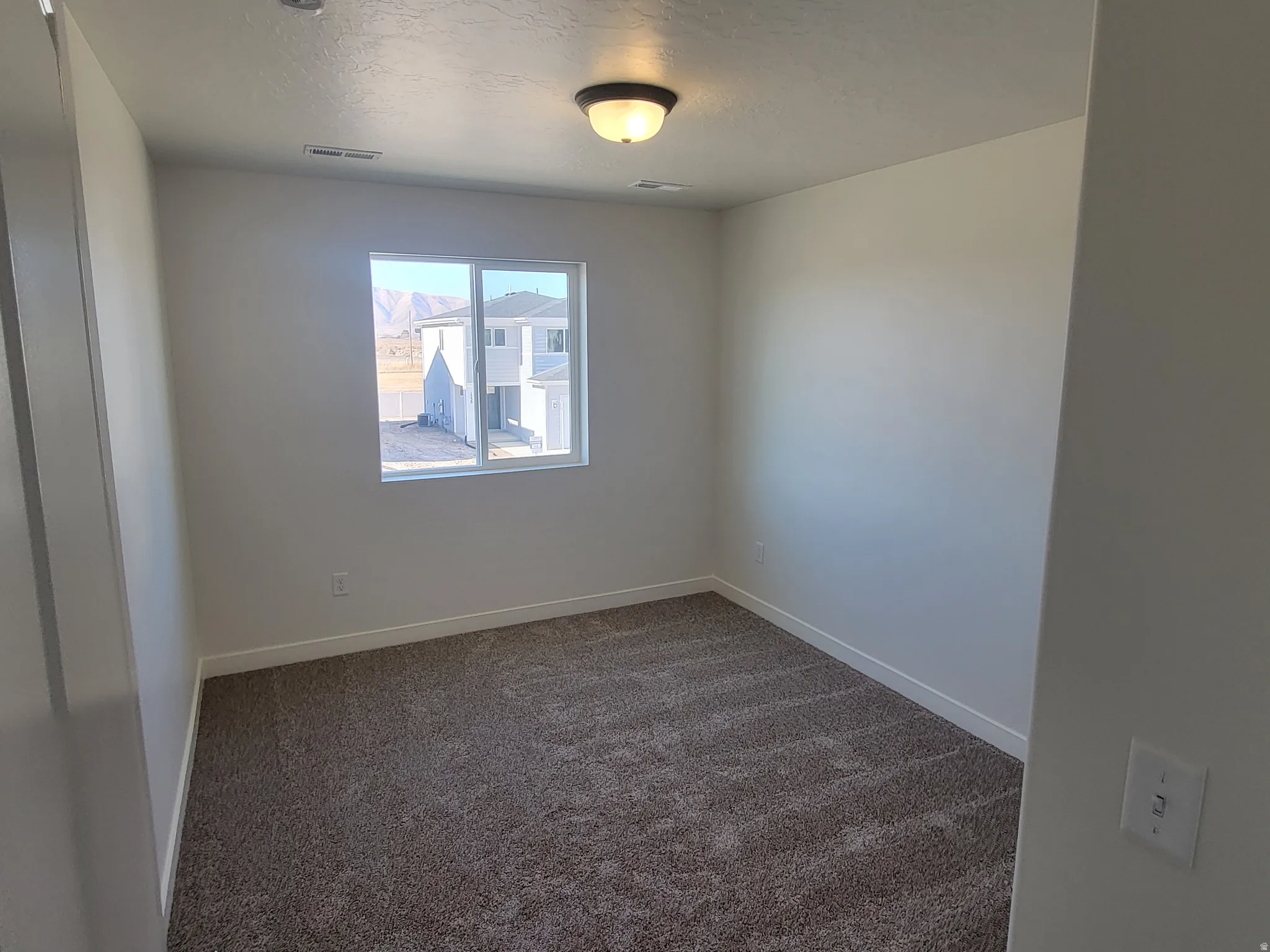 Unfurnished room with dark colored carpet and a textured ceiling