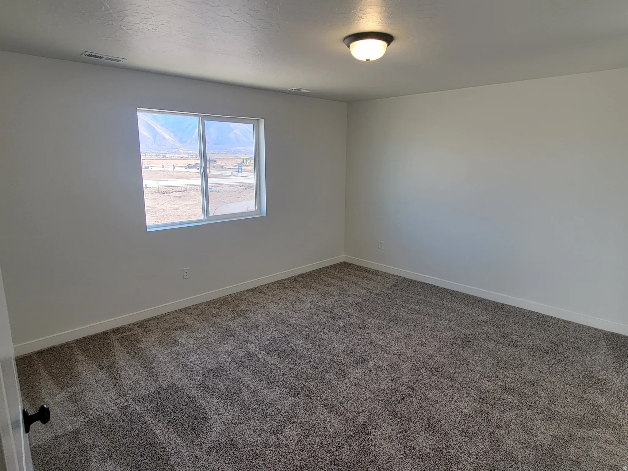 Carpeted spare room featuring baseboards and a textured ceiling