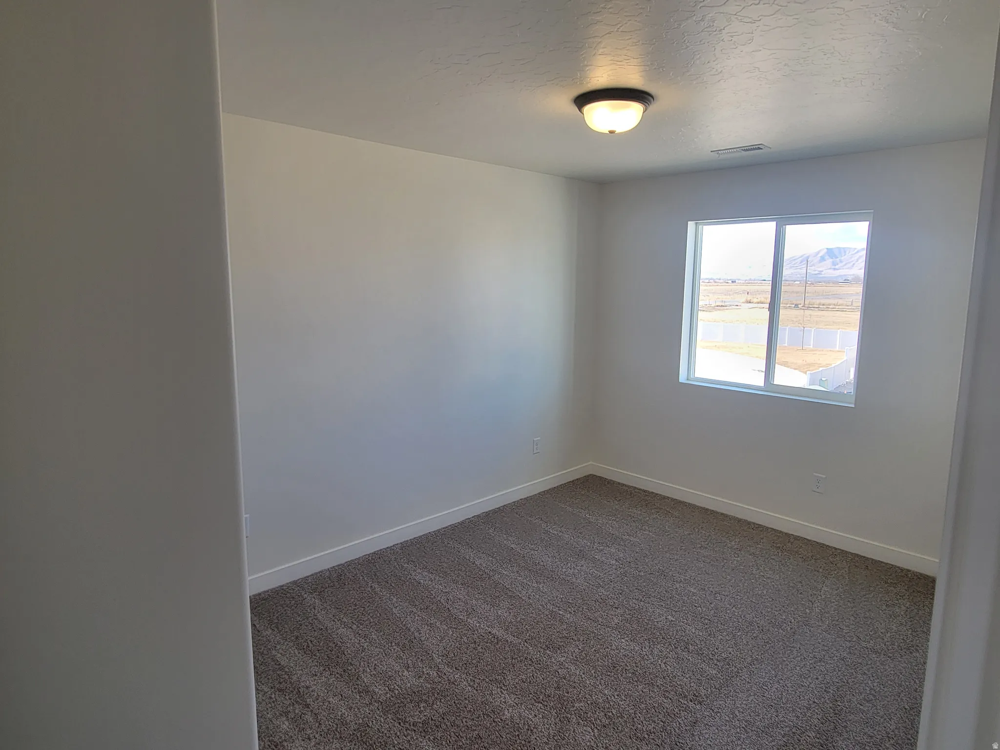 Unfurnished room with a textured ceiling and dark carpet