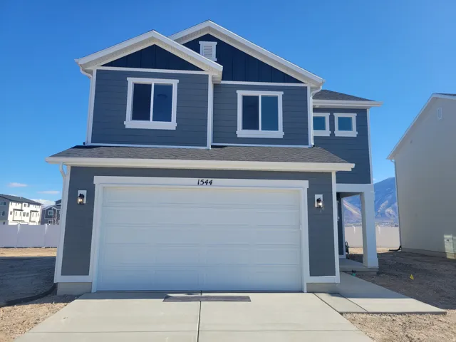 View of front of home with roof with shingles, an attached garage, driveway, and board and batten siding