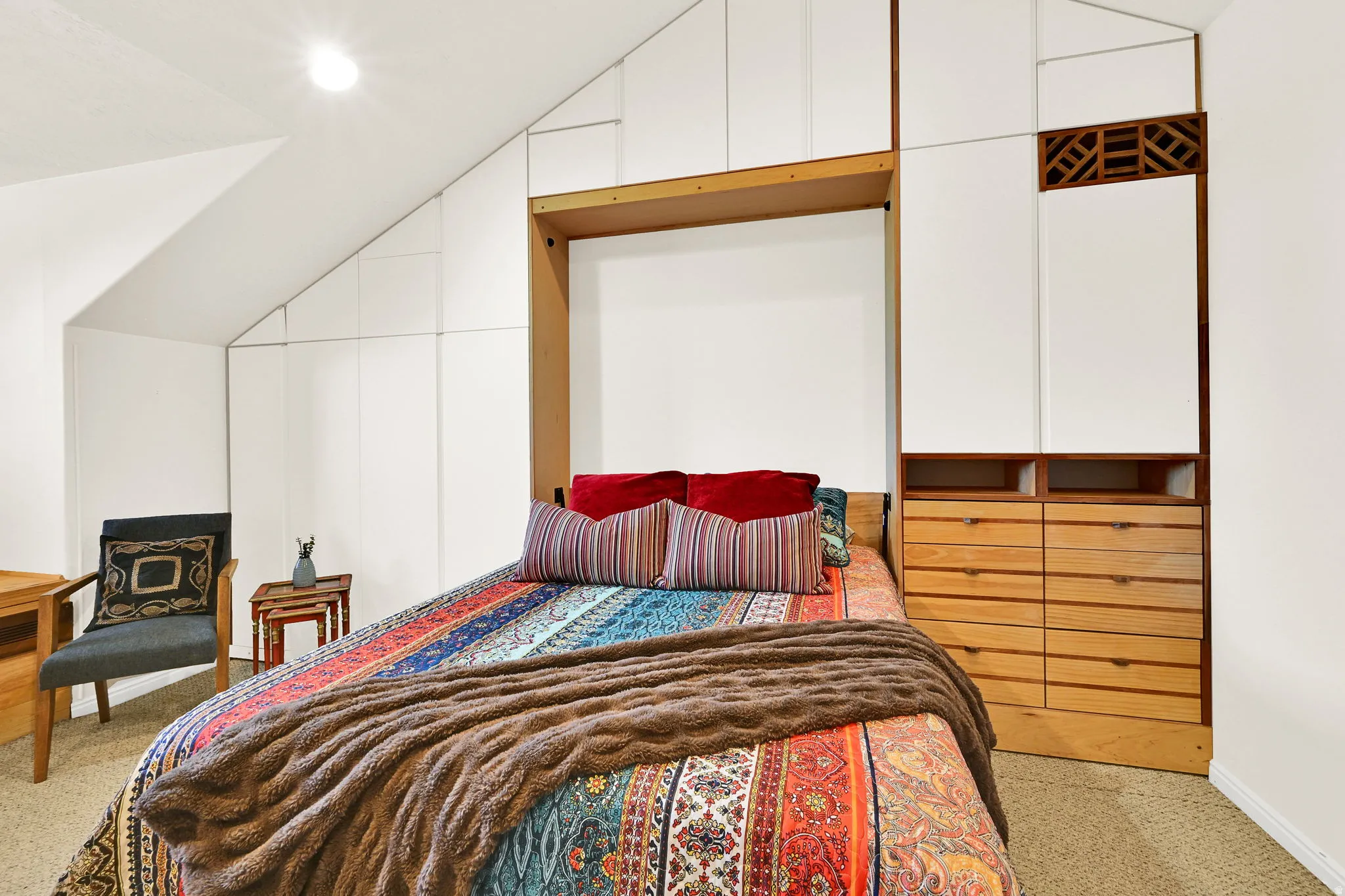 Built-in storage solutions featuring white cabinetry murphy bed and wood-finish drawer units