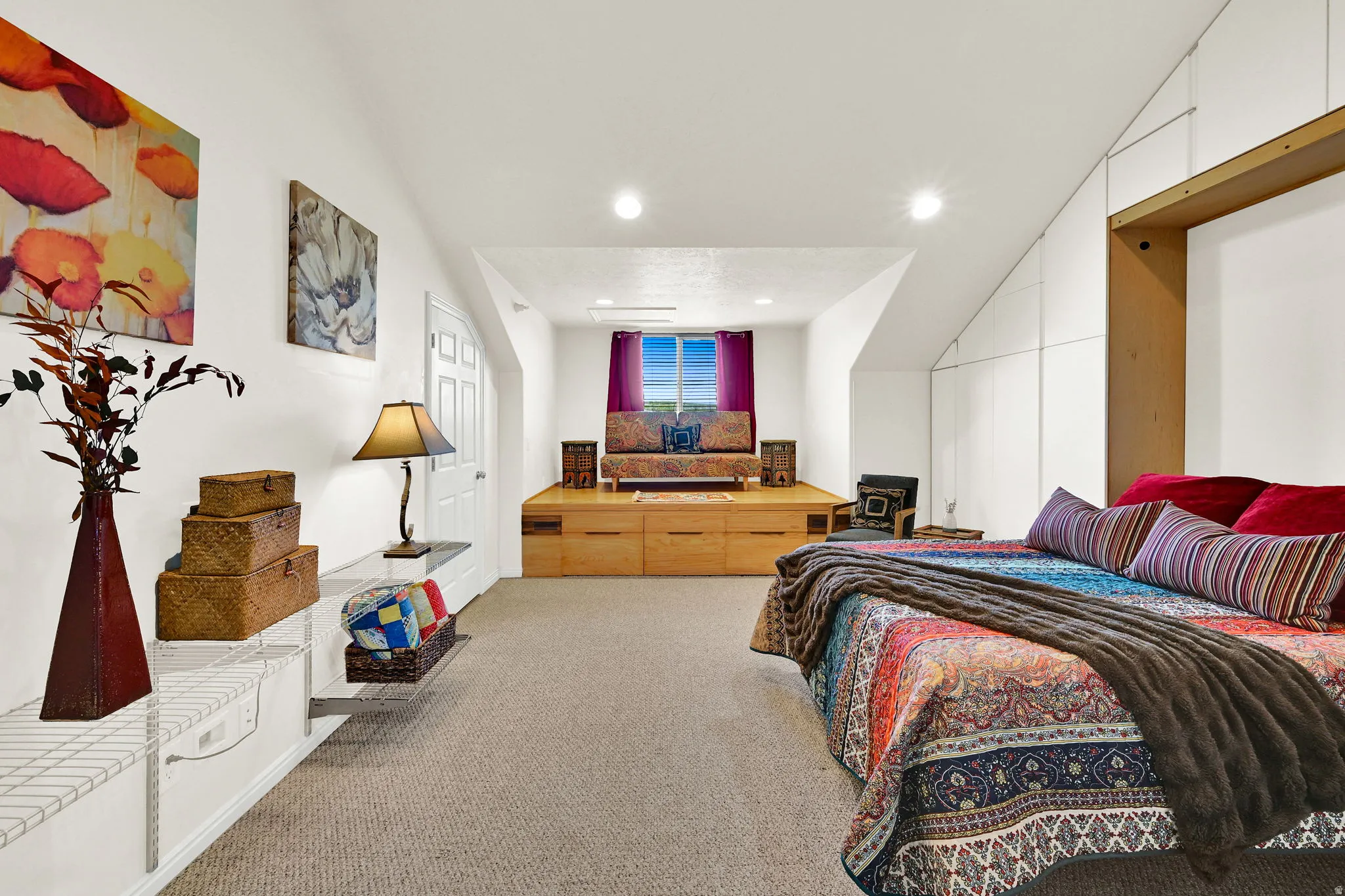 Versatile room featuring an elevated platform with integrated storage, sloped ceilings, recessed lighting, and soft carpet flooring