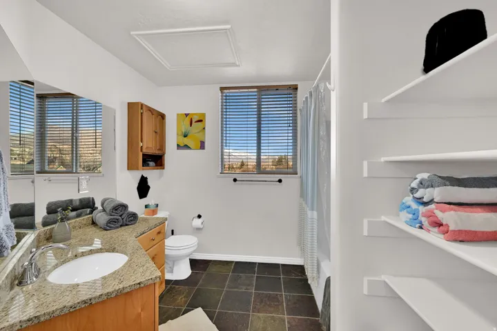 Full bath featuring vanity, shower / bath combo with shower curtain, and stone finish floors