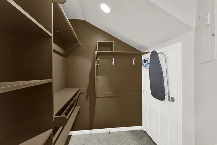 Walk in closet with light colored carpet and lofted ceiling