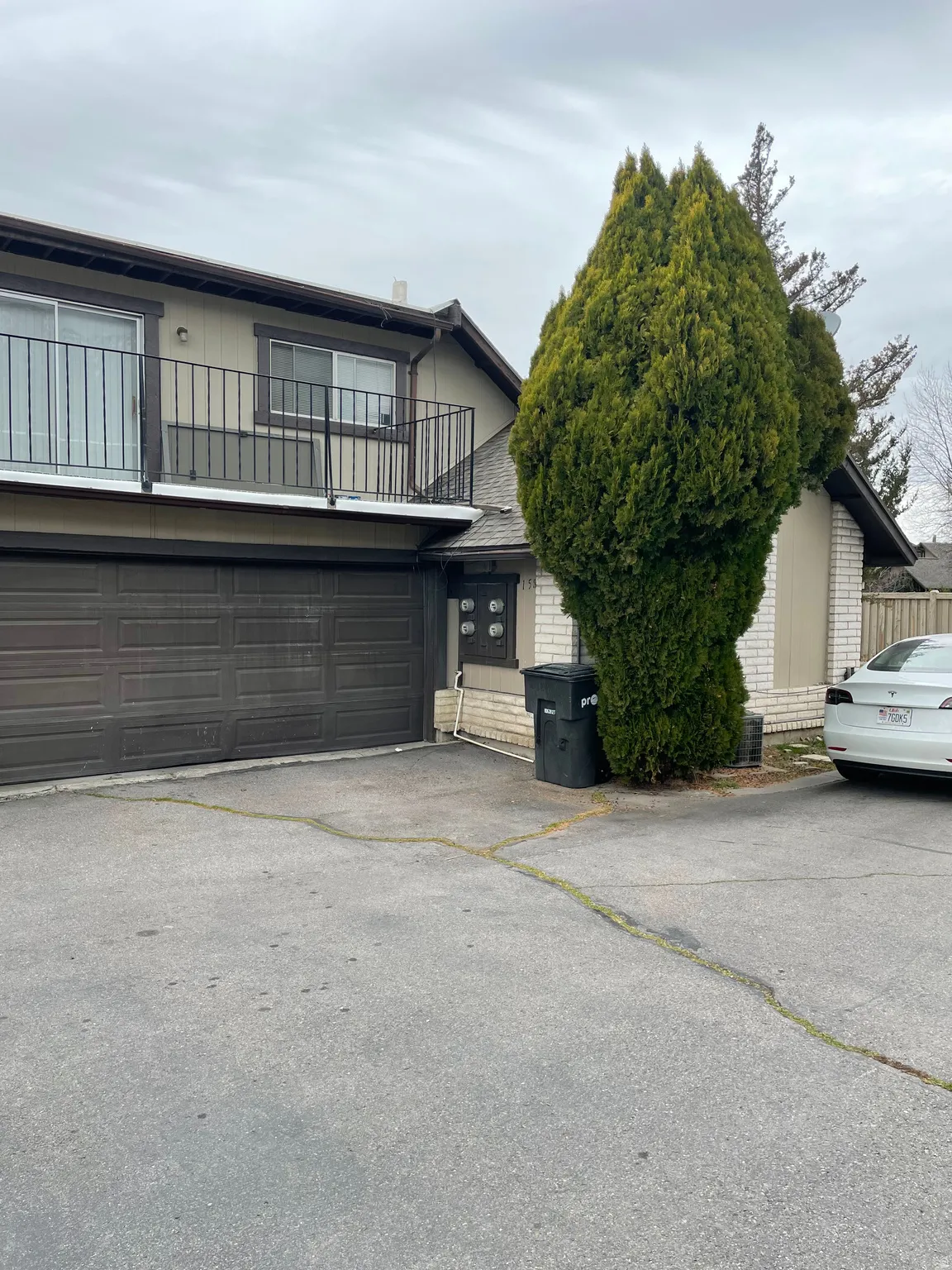 View of front facade with a garage, driveway, and a balcony