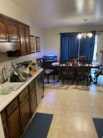 Kitchen featuring light countertops, light flooring, dark wood finish cabinets, dishwasher, and suspended lighting