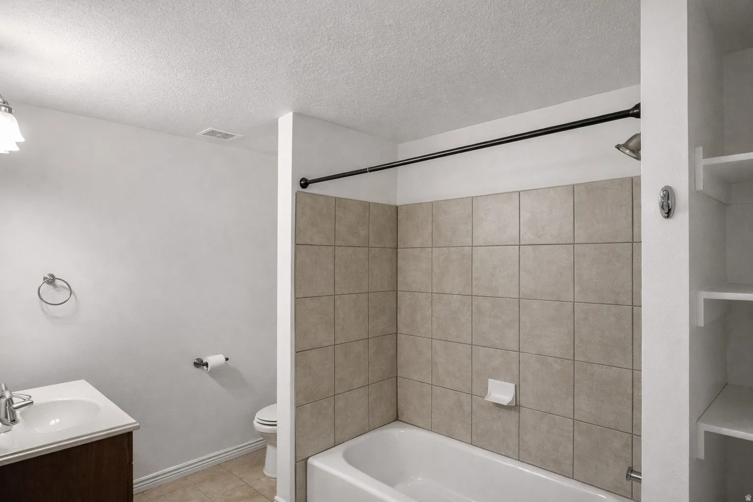 Full bathroom featuring vanity, shower / bath combination, a textured ceiling, and light tile patterned floors