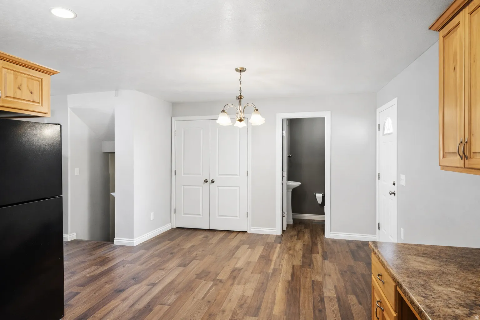 Unfurnished dining area with a chandelier and dark wood-style flooring