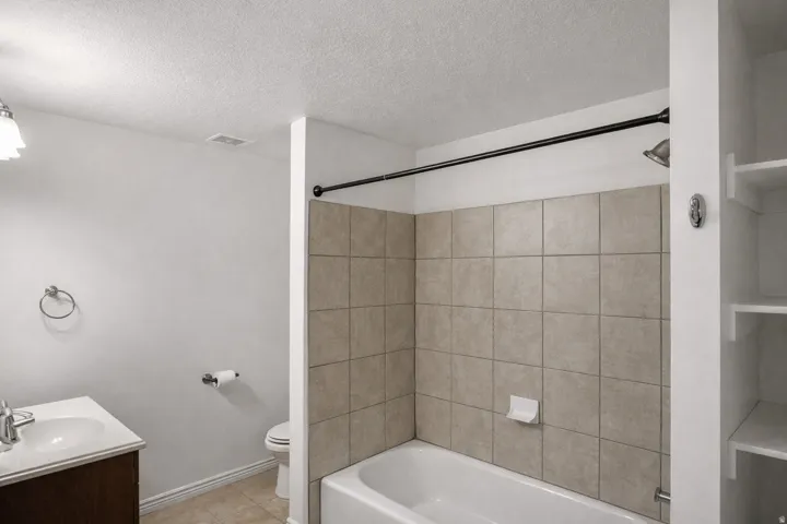 Full bathroom featuring vanity, shower / bath combination, a textured ceiling, and light tile patterned floors